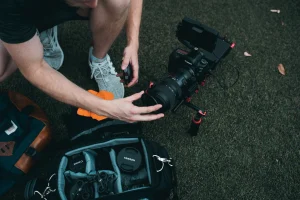 A man is packing camera lens into a bag to bring for hiking