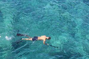 Man Snorkeling in Water with selfie stick and iPhone