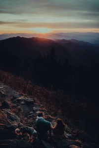 Couple sitting on top of a mountain at sunset