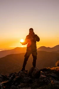 Man Posing on Top of a Mountain with the sun kissed picture