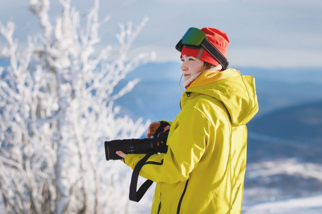 A girl is holding a camera on the mountain