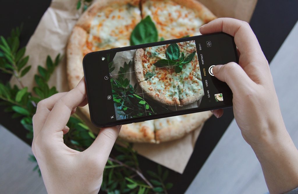holding a smartphone to take food photos