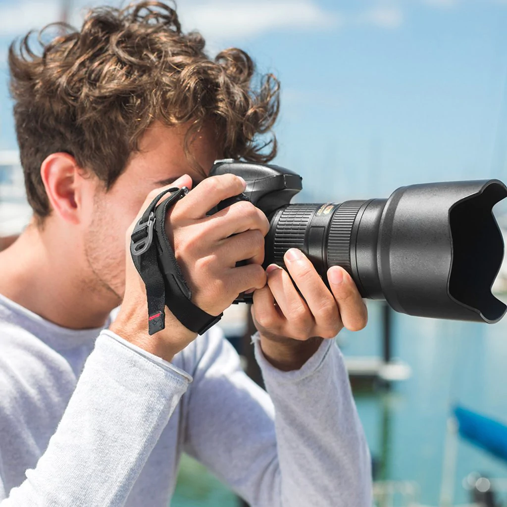 A man using a camera with Peak Design Clutch CL – 2 Hand strap