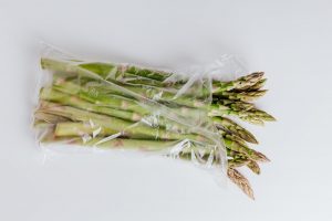A white background is used to isolate a polyethylene bag of asparagus stems