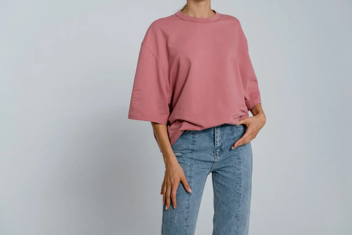 Woman in Pink Crew Neck T-shirt and Blue Denim Jeans in a plain background