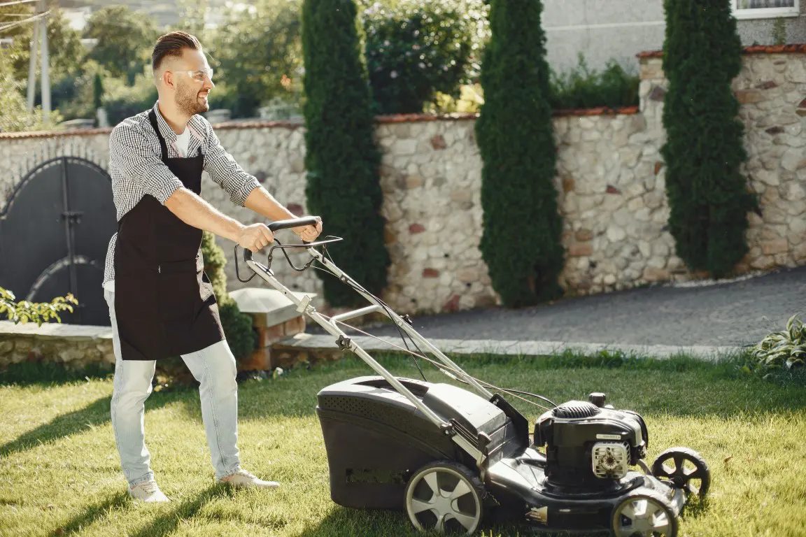 Man in a white and black long sleeve shirt holding a lawnmower