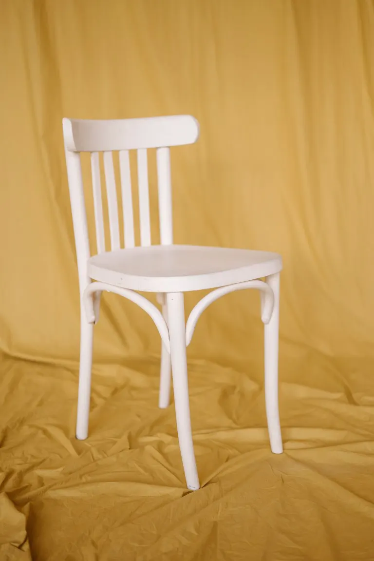Photo of a white chair on a mustard cloth backdrop