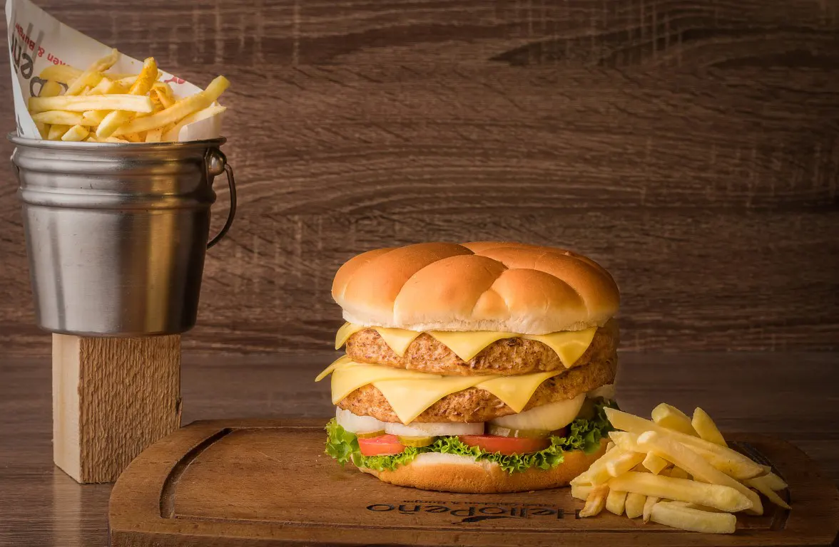 A food photo of a delicious cheeseburger and french fries on a wooden surface