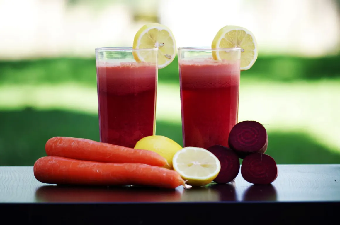 A food photo of carrot and beetroot beside lemon slices with glasses of juice