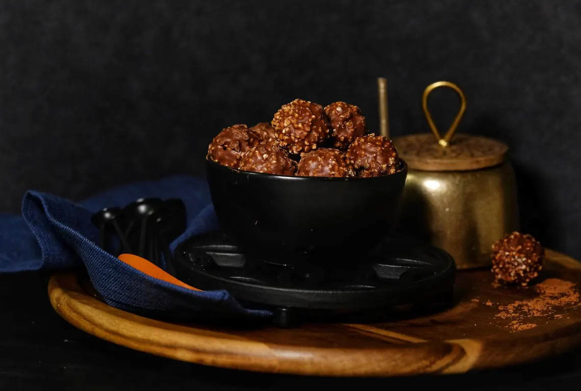 A food photo of chocolate on a black bowl over a dark backdrop