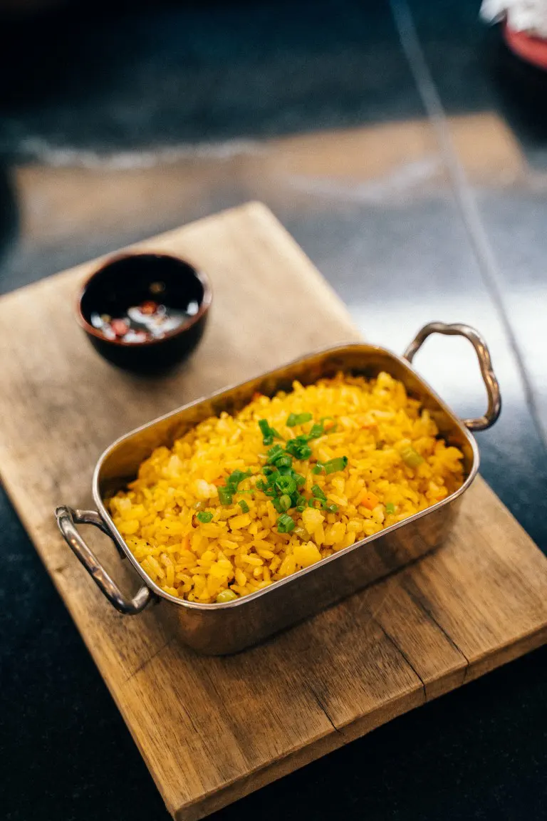 A Vintage food photo of yellow fried rice in a metal tray