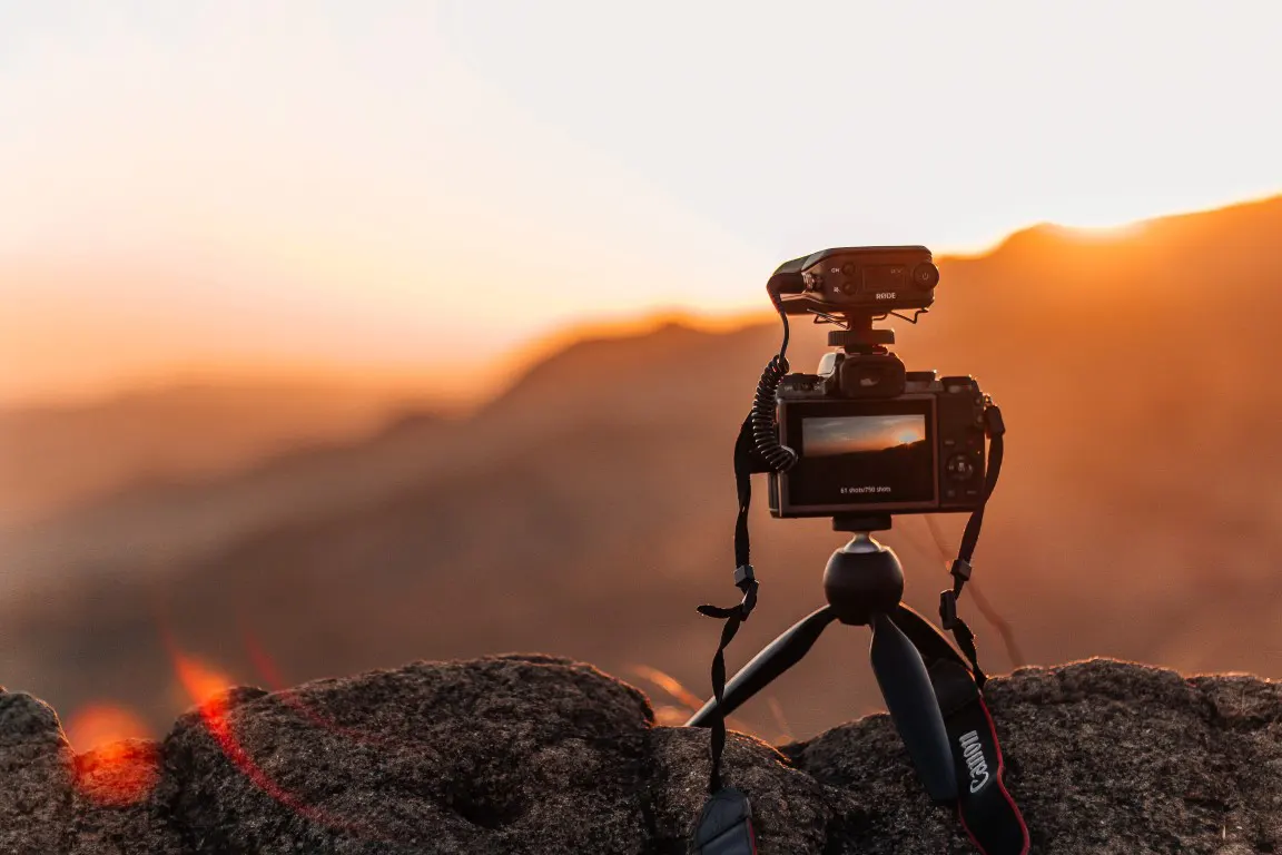A small tripod holding a camera on a top of mountain