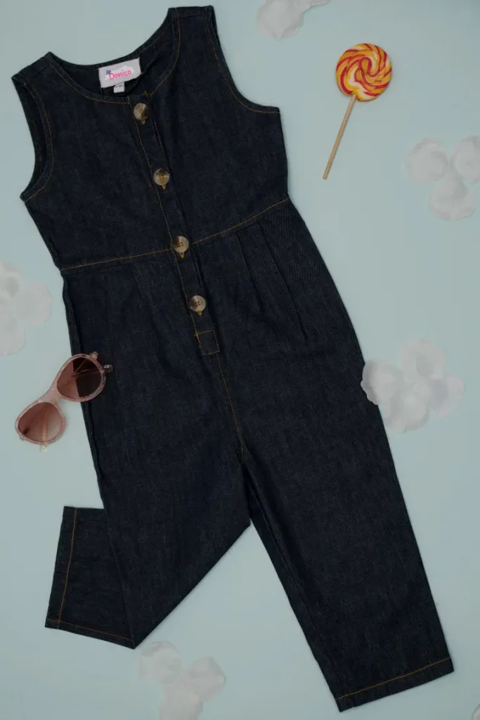 A girls denim jumpsuit and sunglasses on flat lay style