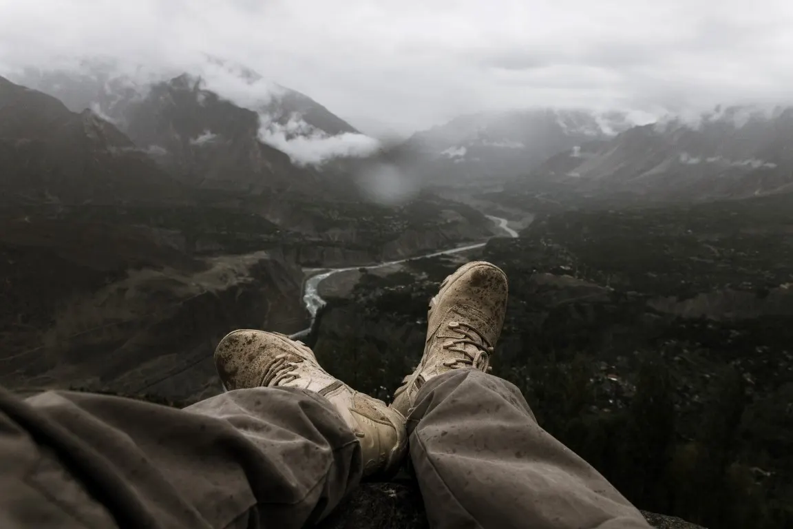 A hiker is hanging his feet over a ledge
