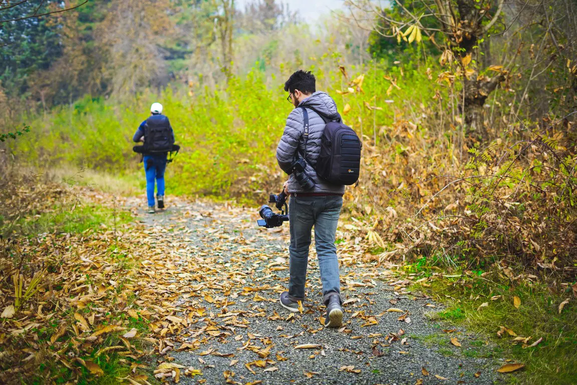 A man carrying a camera walking on the hiking trail in the forest