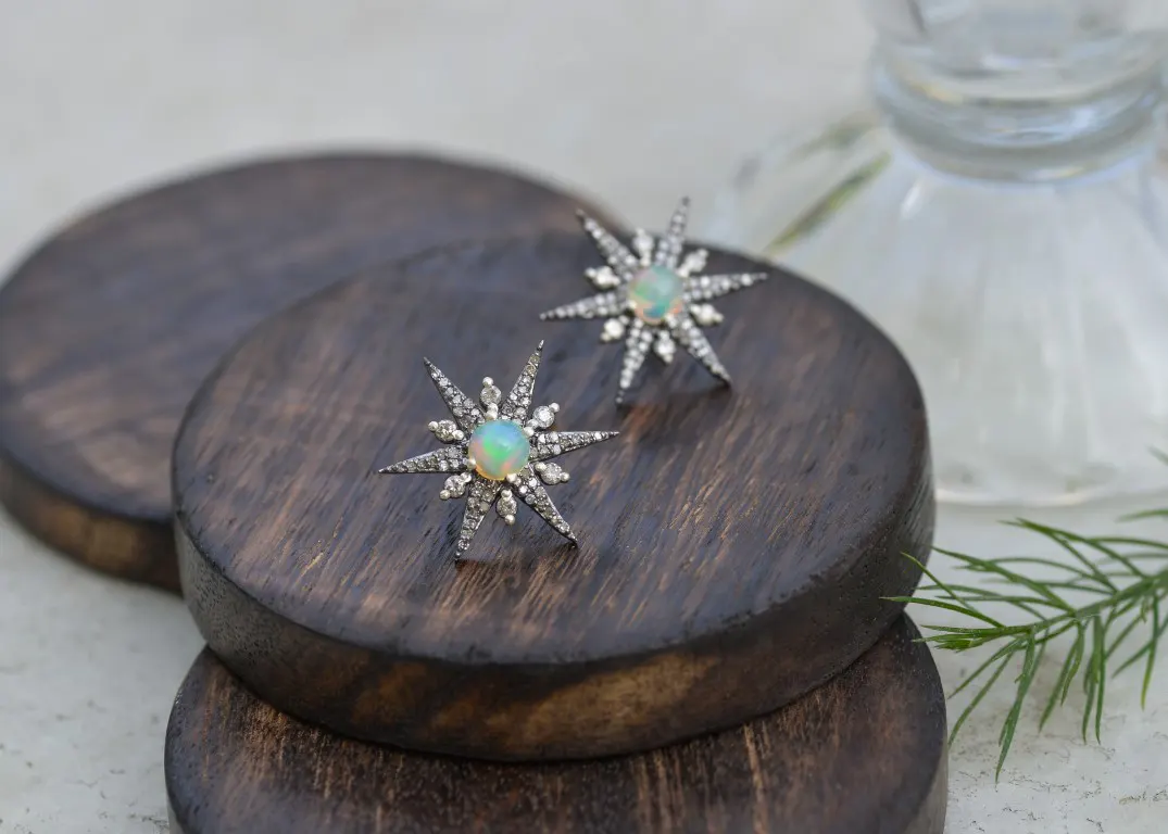 A jewelry photograph of a pair of earrings on wooden props