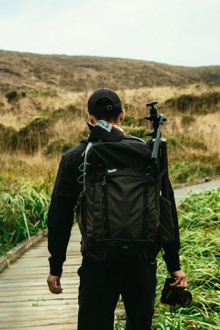 Man carrying a backpack with camera accessories on his backpacking trial