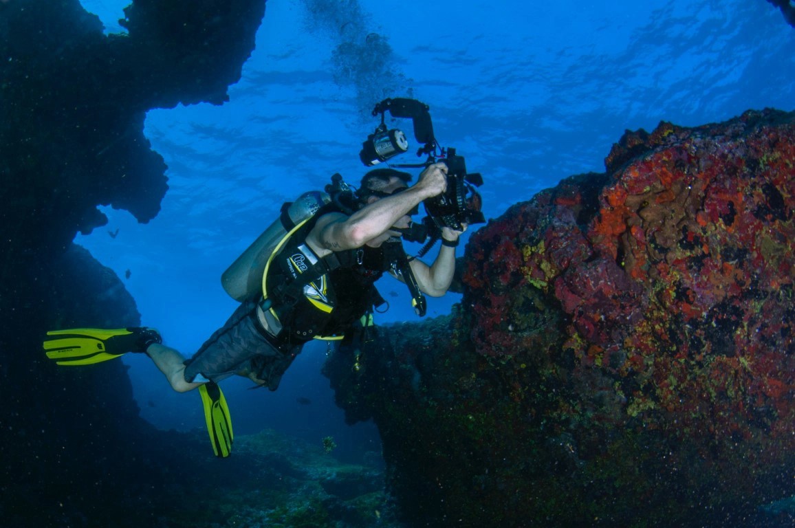 Scuba diving moment with underwater housing and camera in medium depth seawater