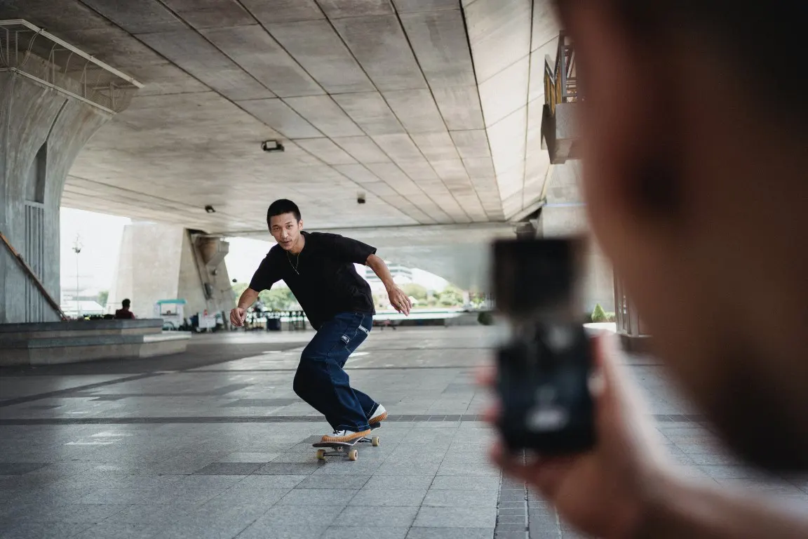 Person taking photo of skateboarder in bad light condition