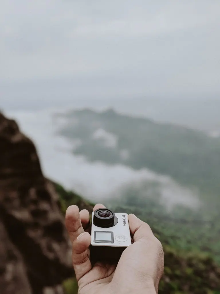Holding a GoPro camera against a nature landscape backdrop